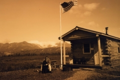 In the middle of nowhere a small log cabin with a US flag flying. Dan the driver has attracted a black newfoundland dog that appeared out of the blue
