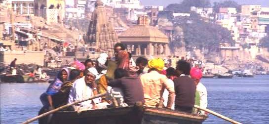 Boat trip, Varanasi, a crowd of devotees being rowed along the Ganges riverbank, where bathing steps and temples crowd together